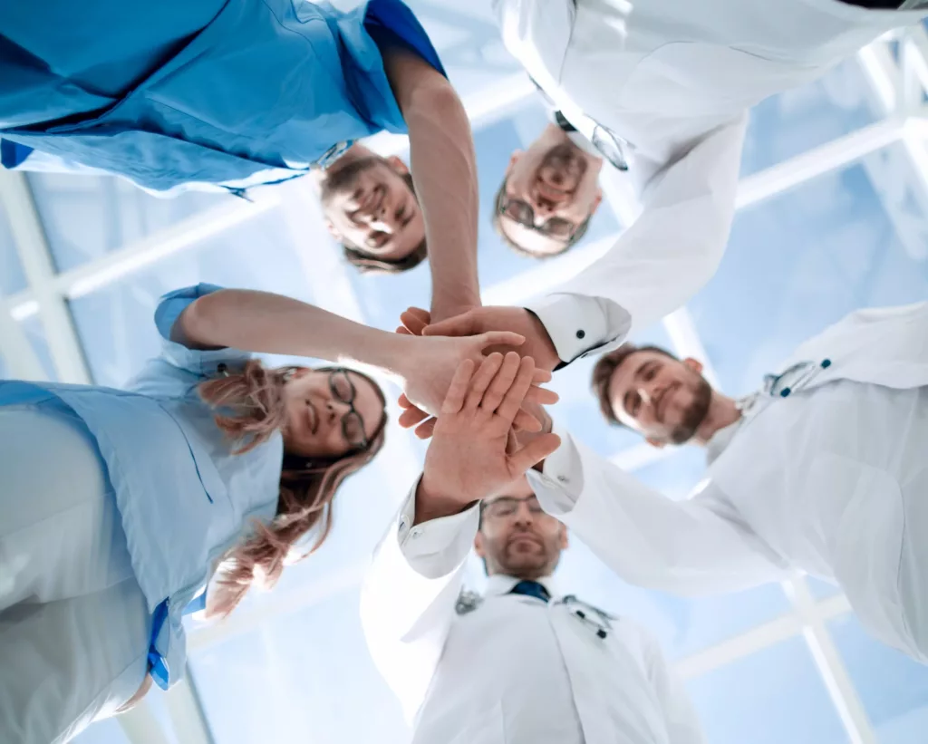 Équipe de docteurs qui se tiennent la main pour illustrer la collaboration médicale.