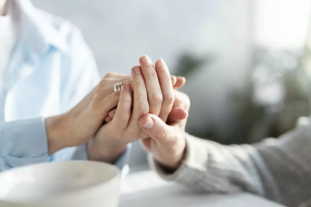 Personne plus jeune tenant la main à une personne âgée, représentant le soutien aux personnes âgées.